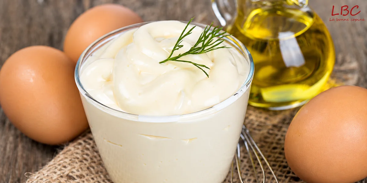 Mayonnaise pour accompagner une salade de crevettes, avec trois œufs et une bouteille d’huile.