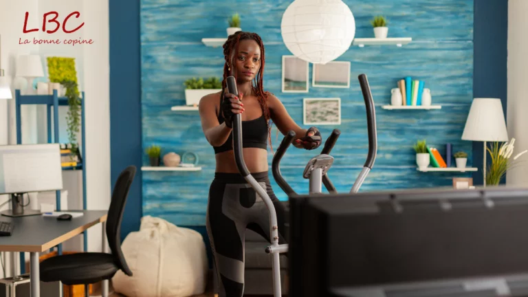 Une femme en pleine séance d’entraînement sur un vélo elliptique, installée dans un salon au design moderne. Une scène qui allie bien-être, motivation et confort à domicile | labonnecopine.com