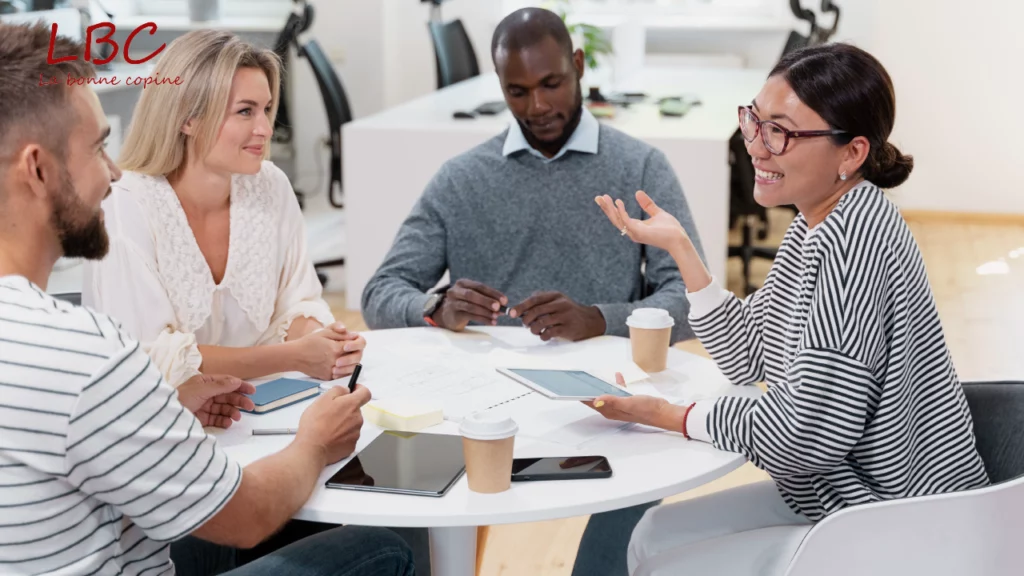 Autour d’une table, une équipe en pleine réunion combine tablettes numériques et documents papier pour avancer dans une réflexion collaborative et structurée | labonnecopine.com