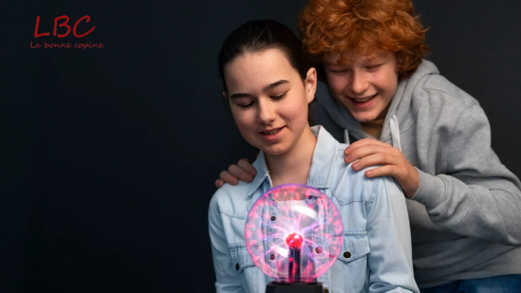 Face à une sphère plasma éclatante, deux personnes observent avec curiosité les filaments lumineux qui réagissent au toucher, illustrant l’émerveillement face aux phénomènes scientifiques | labonnecopine.com