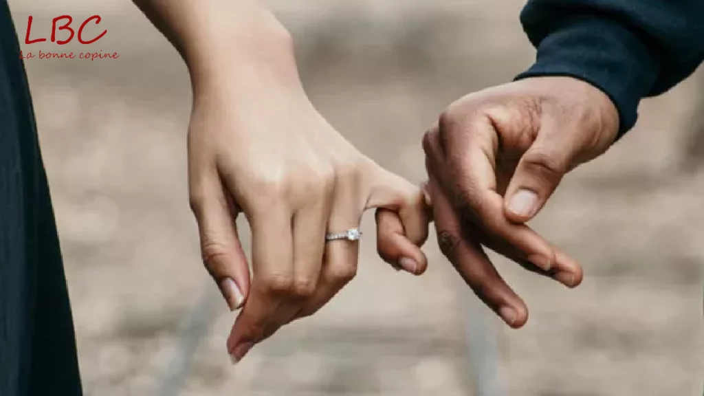 Deux mains se rejoignent dans un geste tendre et symbolique. Sur l’une d’elles, une élégante bague de fiançailles brille discrètement, signe d’un engagement précieux. Ce simple contact raconte une histoire d’amour, de promesse et de connexion profonde entre deux personnes | labonnecopine.com