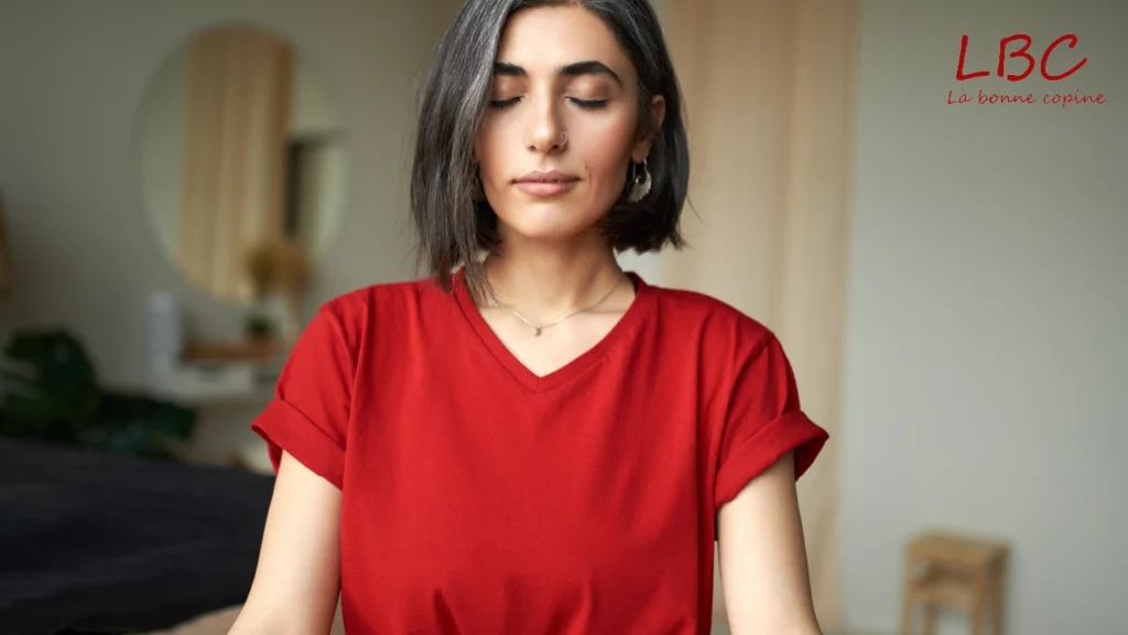Vrouw in rood T‑shirt medite, straalt innerlijke rust en connectie uit