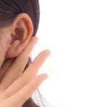 Le gros plan révèle une main délicatement posée près de l’oreille d’une femme, capturant un moment d’écoute silencieuse et attentive. Ce geste simple, presque instinctif, incarne la qualité d’une présence véritable, où l’on ne se contente pas d’entendre les mots, mais où l’on s’ouvre pleinement à ce que l’autre exprime, avec attention, respect et sensibilité | labonnecopine.com