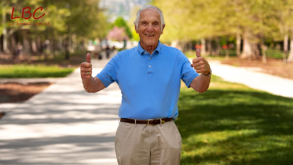 A smiling senior lifts a thumb in a sun‑lit park, embodying positivity, vitality and the joy of living in the moment at any age.