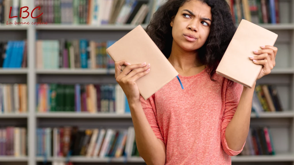 Debout devant une étagère remplie de livres, une personne tient deux ouvrages entre ses mains, comme hésitant entre deux lectures. Une scène simple qui évoque la curiosité, le choix et l’amour des livres | labonnecopine.com Debout devant une étagère remplie de livres, une personne tient deux ouvrages entre ses mains, comme hésitant entre deux lectures. Une scène simple qui évoque la curiosité, le choix et l’amour des livres.