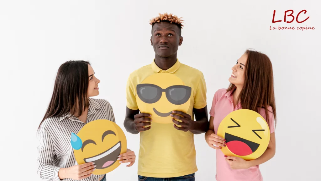Three smiling people hold emoji balloons, playfully illustrating how positive emotional expression fuels authentic connection in nonviolent communication.