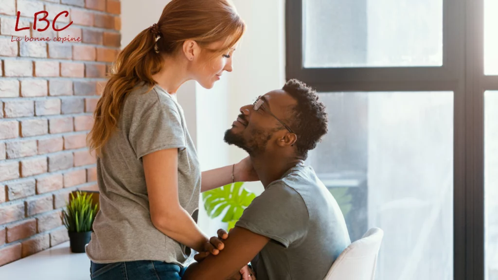 Un couple partage un moment complice près d’une fenêtre | labonnecopine.com