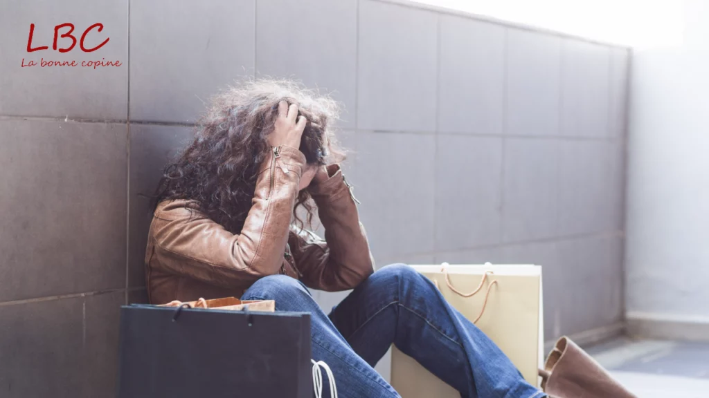 Assise par terre, adossée à un mur, une femme laisse transparaître son stress après une longue virée shopping | labonnecopine.com