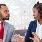 Deux collègues en tenue formelle échangent quelques mots lors d’un moment de discussion professionnelle | labonnecopine.com