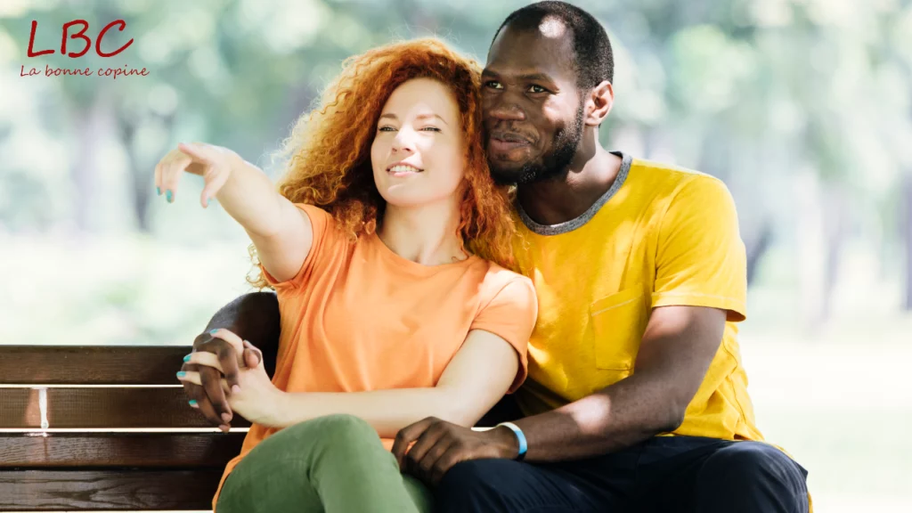 Un couple complice sur un banc, elle montre l&rsquo;horizon pendant qu&rsquo;il l&rsquo;enlace tendrement | labonnecopine.com 