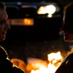 Deux personnes se font face dans une lumière tamisée, leurs profils à peine éclairés par la lueur dorée d’un feu ou d’une source chaleureuse . Leurs visages, partiellement illuminés, baignent dans une atmosphère intime et apaisante | labonnecopine.com