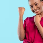 Une femme souriante lève le poing avec assurance, exprimant une énergie positive et un sentiment de victoire | labonnecopine.com