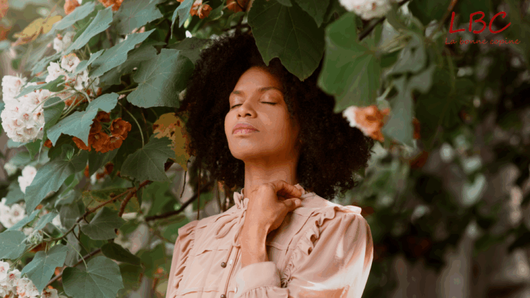 Dans un cadre naturel vibrant de vie, une femme se tient debout, entourée d’un mélange généreux de fleurs colorées et de feuillages abondants. Sa posture paisible et son expression sereine évoquent un profond sentiment de connexion à la nature, illustrant un moment d’équilibre et de ressourcement au cœur d’un environnement végétal apaisant | labonnecopine.com