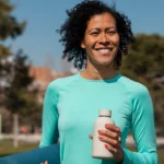 Energy, well-being and simplicity: a smiling woman in turquoise sportswear enjoys a moment of relaxation in a sunny city park | labonnecopine.com