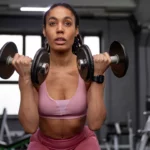 Concentration, force et confiance : en tenue de sport rose, elle enchaîne les curls dans une salle de musculation contemporaine, symbole de persévérance et de transformation | labonnecopine.com