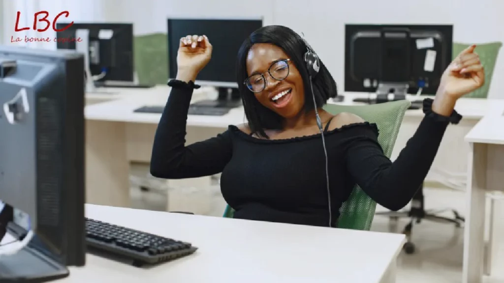 Cheerful woman with headphones raises her arms in victory in a modern office | labonnecopine.com/en  
