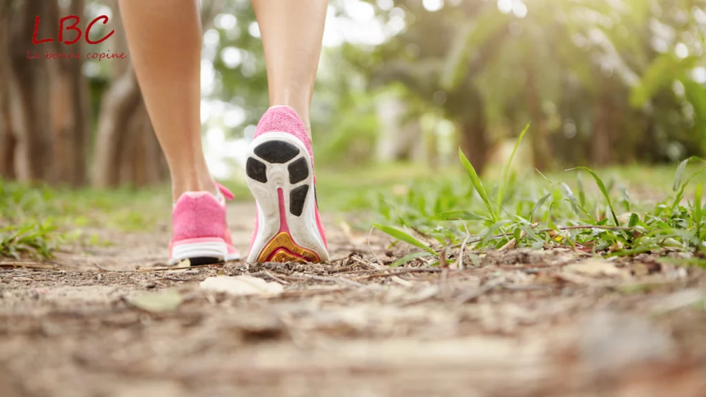 A person walking on a natural trail wearing pink athletic shoes, embodying mindful movement and steady breathing.