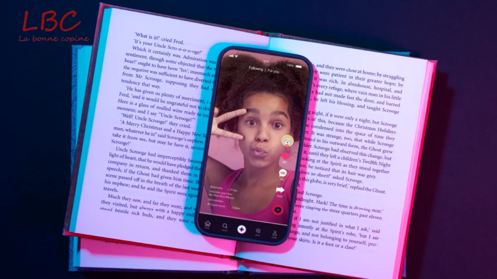 Smartphone rust op een open boek, met een video‑reading gedeeld via sociale media – een samensmelting van traditionele literatuur en digitale gewoonten | labonnecopine.com