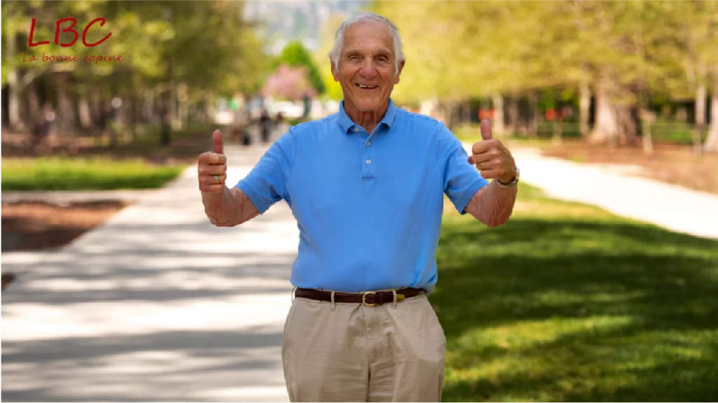 A smiling senior man in a blue polo gives a spirited thumbs-up in a sun-drenched park. A scene full of good humor and vitality | labonnecopine.com/en