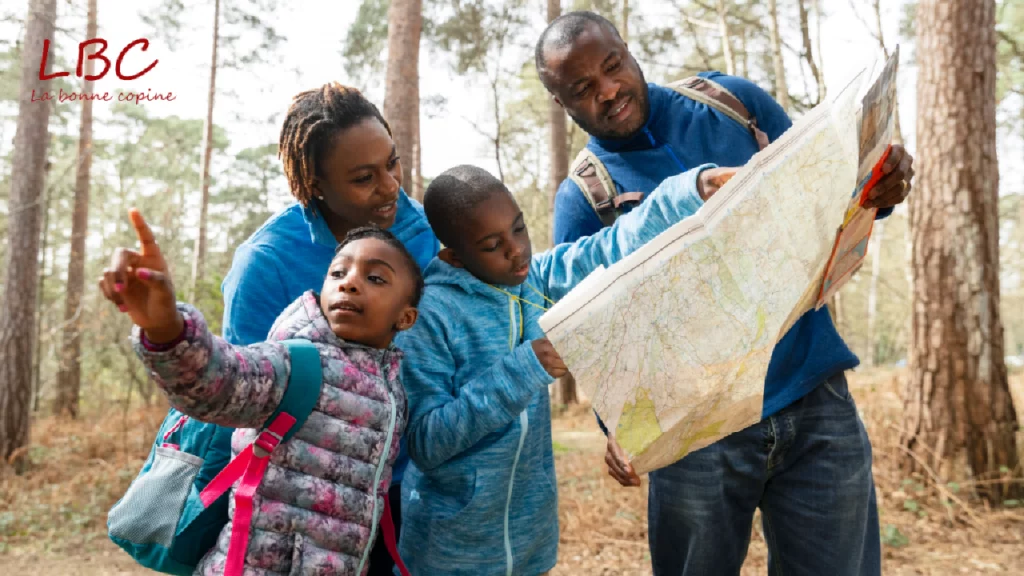 While hiking in the forest, a family with two children carefully examines a map to choose their route | labonnecopine.com/en