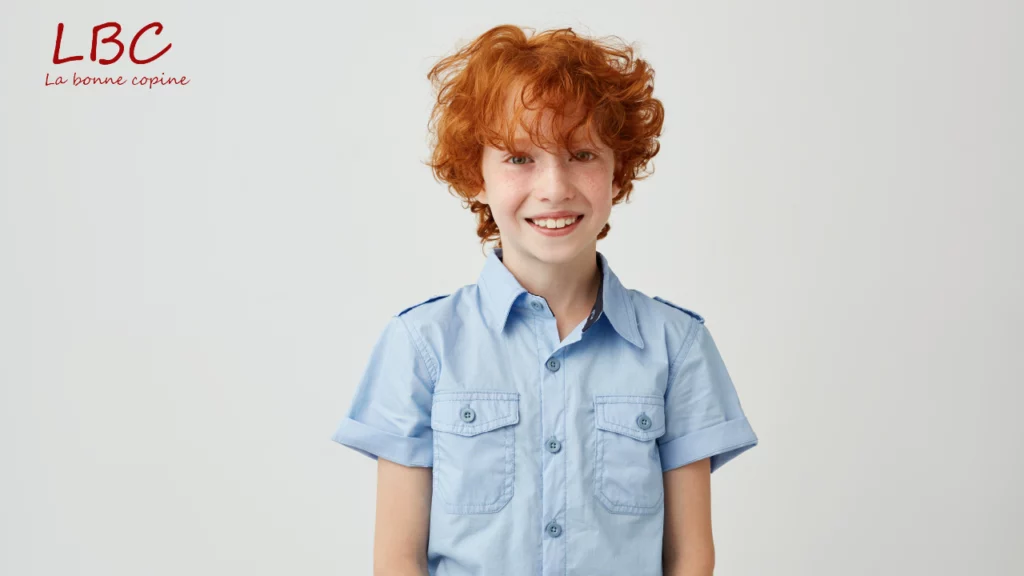 Young boy with curly red hair smiling in light blue shirt | labonnecopine.com/en